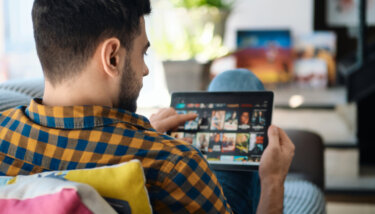 featured image for the ott live streaming blog post showing a man selecting an ott app on his tablet