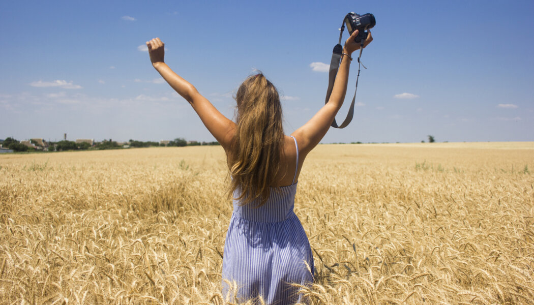 image of video creator in a golden field under a blue sky raising her hands in triumph
